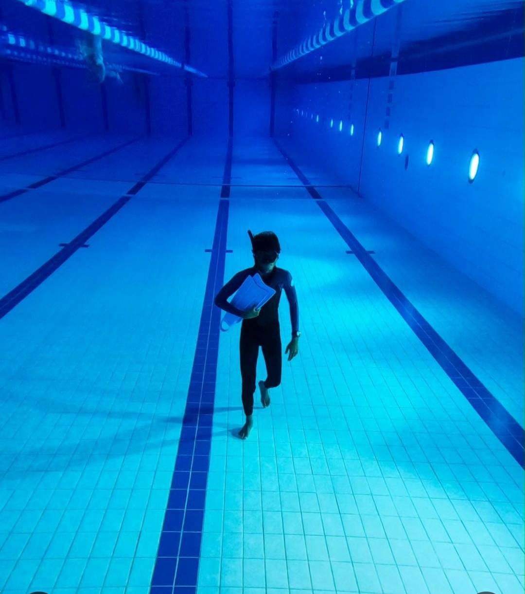 A diver carrying a waterproof journal beneath the surface of a pool